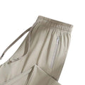 A pair of light beige athletic pants with an elastic waistband, drawstring, and zippered side pocket.
