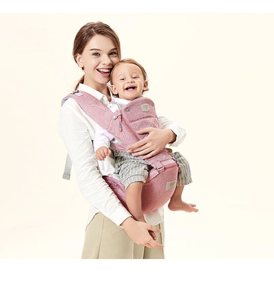 Woman holding a baby in a pink baby carrier against a white background
