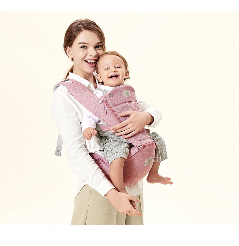 Woman holding a baby in a pink baby carrier against a white background