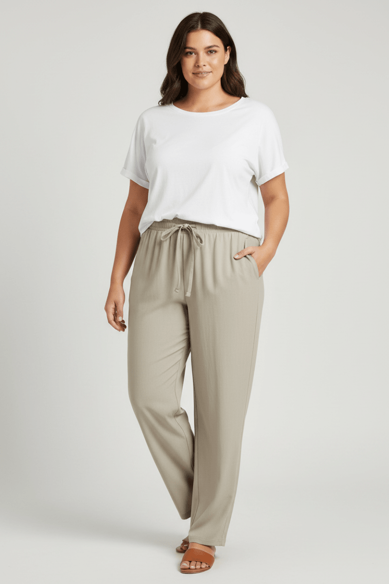 A model wearing pair of light beige athletic pants with an elastic waistband, drawstring, and zippered side pocket,