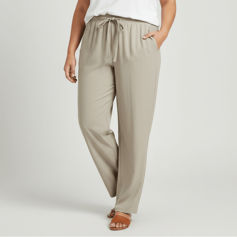 A pair of light beige athletic pants with an elastic waistband, drawstring, and zippered side pocket,