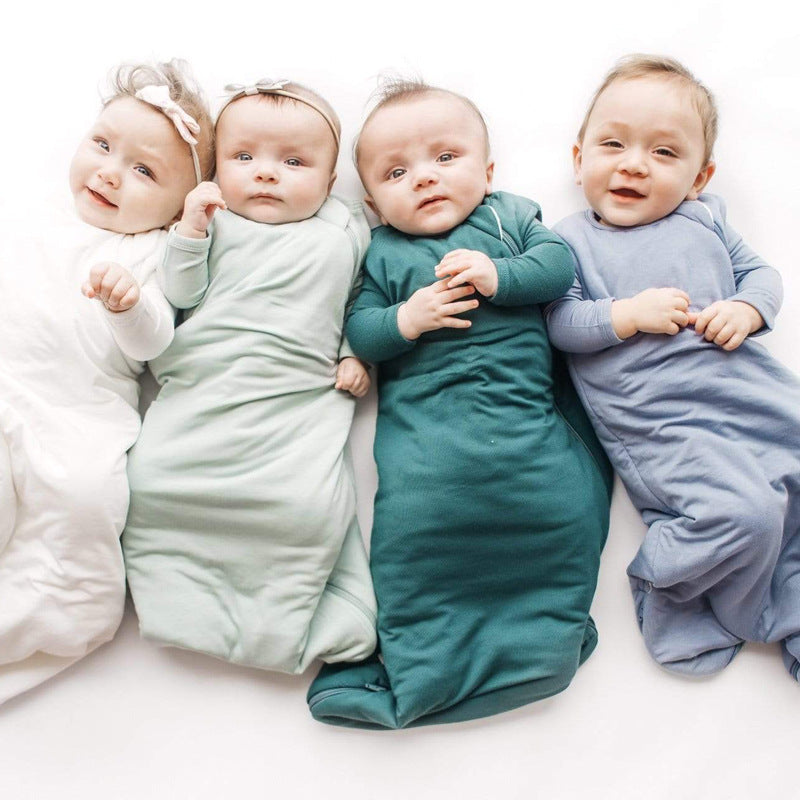 Four babies in colorful swaddles lying on a white surface